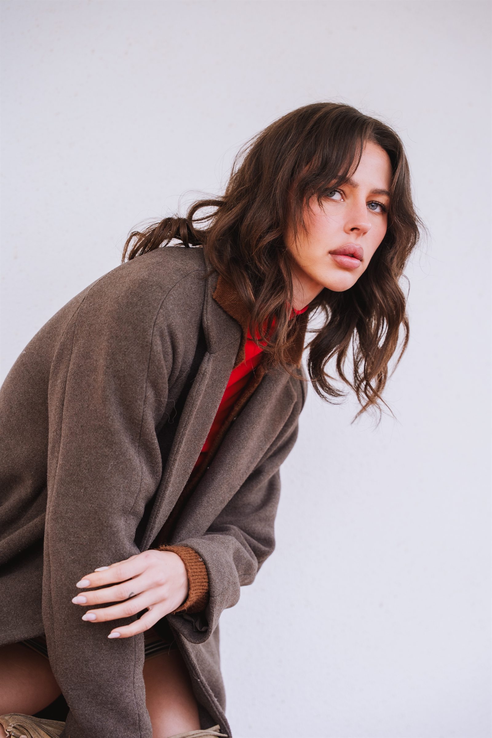Editorial portrait — model in a brown wool coat against a white wall