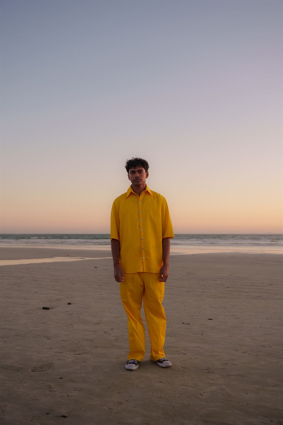 Portrait photography — figure in a yellow suit standing on the beach at sunset